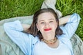 Young smiling woman is relaxing outdoors and having picnic, she is lying on blanket on the grass Royalty Free Stock Photo