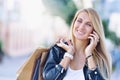 Young smiling woman with shoping bags talk by cellular telephone.