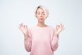 Young smiling woman with short colored hairstyle meditating, holding her hands in yoga gesture, feeling calm Royalty Free Stock Photo