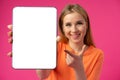 Young smiling woman showing digital tablet with blank screen against pink background Royalty Free Stock Photo