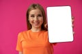 Young smiling woman showing digital tablet with blank screen against pink background Royalty Free Stock Photo