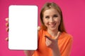 Young smiling woman showing digital tablet with blank screen against pink background Royalty Free Stock Photo