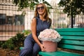 Young smiling woman sits on bench with tender flower composition in her hands