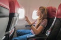 A young smiling woman sits inside the plane and takes a photo from the window Royalty Free Stock Photo