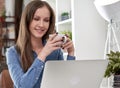 Young smiling woman sitting at desk, drinking coffee at home in the morning, working on laptop computer in the living room Royalty Free Stock Photo