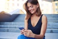 Young smiling woman sitting outdoors and typing a meesage on mob Royalty Free Stock Photo