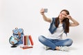 Young smiling woman student doing taking selfie shot on mobile phone showing victory sign near globe, backpack, school Royalty Free Stock Photo