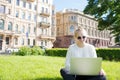 Young smiling woman student learning on-line via laptop computer, sitting on university campus. Royalty Free Stock Photo