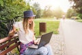 Young woman student sitting on park bench working on laptop computer Royalty Free Stock Photo