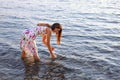 Young smiling woman in summer dress stands barefoot in water and washes her hands Royalty Free Stock Photo