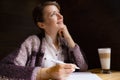 Young smiling woman thinking with pen and open notebook. Thoughtful girl portrait. Journalist and writer concept. Business lifesty