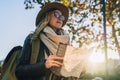 Young smiling woman travels in hat and eyeglasses stands on city street, holding map in her hands.Hipster girl walks. Royalty Free Stock Photo