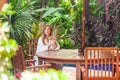 Young smiling woman on tropical vacation in modern luxury resort. Female traveler in bathrobe relax near swimming pool Royalty Free Stock Photo