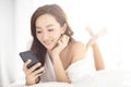 smiling woman watching mobile phone on bed Royalty Free Stock Photo