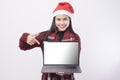 Young smiling woman wearing red Santa Claus hat making with laptop screen mock up  on white Royalty Free Stock Photo