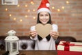 Young smiling woman wearing red Santa Claus hat showing a heart shaped model on Christmas day, holiday concept Royalty Free Stock Photo