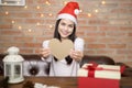 Young smiling woman wearing red Santa Claus hat showing a heart shaped model on Christmas day, holiday concept Royalty Free Stock Photo