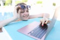 Young smiling woman is working on laptop while in pool Royalty Free Stock Photo