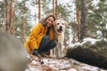 Young smiling woman in yellow jacket with big kind white dog Labrador walking in the winter forest Royalty Free Stock Photo