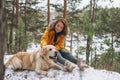 Young smiling woman in yellow jacket with big kind white dog Labrador walking in the winter forest Royalty Free Stock Photo