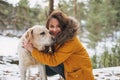 Young smiling woman in yellow jacket with big kind white dog Labrador walking in winter forest Royalty Free Stock Photo