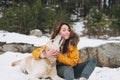 Young smiling woman in yellow jacket with big kind white dog Labrador walking in the winter forest Royalty Free Stock Photo