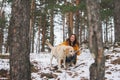 Young smiling woman in yellow jacket with big kind white dog Labrador walking in winter forest Royalty Free Stock Photo