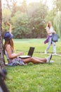 Young woman student sitting on park bench working on laptop computer Royalty Free Stock Photo