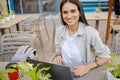 Beautiful entrepreneur using laptop during lunch in outdoor cafe, elegant businesswoman holding coffee cup working in city street. Royalty Free Stock Photo