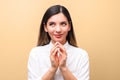 Young sneaky woman in white shirt, scheming something new for her business against orange background Royalty Free Stock Photo