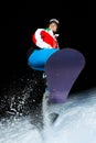 Young snowboarder jumping at night