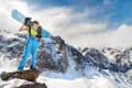 Young snowboarder woman in bikini on the slope looks at the far away against of snowy mountains in sunlight Royalty Free Stock Photo