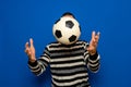 Young soccer fan in striped jersey cheers to support favorite team holding face hidden behind soccer ball isolated on Royalty Free Stock Photo