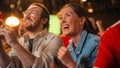 Young Soccer Fans Couple Watching a Live Football Match in a Sports Bar. Crowd with Colored Faces Royalty Free Stock Photo