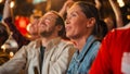 Young Soccer Fans Couple Watching a Live Football Match in a Sports Bar. Crowd with Colored Faces Royalty Free Stock Photo