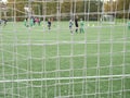 Young soccer team on playground viewed through net Royalty Free Stock Photo