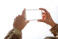 Young soldier holding a mobile phone with blank screen on white background