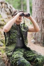 Young soldier or hunter with binocular in forest