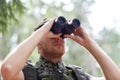 Young soldier or hunter with binocular in forest