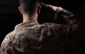 Young soldier saluting standing on black background Royalty Free Stock Photo