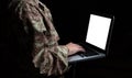 Young soldier working with a laptop computer with blank screen on black background Royalty Free Stock Photo