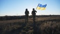 Young soldiers of ukrainian army running with lifted national banner on field. Military woman and man in camouflage Royalty Free Stock Photo