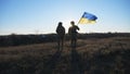 Young soldiers of ukrainian army running with lifted national banner on field. Military woman and man in camouflage Royalty Free Stock Photo