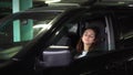 A young solid woman sits in a car in the parking lot and falls asleep. Businesswoman in glasses and a jacket leaned back