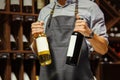 Young sommelier holding bottle of red wine in cellar Royalty Free Stock Photo