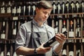 Young sommelier holding bottle of red wine in cellar Royalty Free Stock Photo