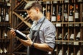 Young sommelier holding bottle of red wine in cellar Royalty Free Stock Photo