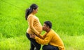 Kneel down and kiss her pregnant belly, countryside nature background