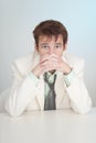 Young sorrowful person in white suit sits at table