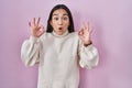 Young south asian woman standing over pink background looking surprised and shocked doing ok approval symbol with fingers Royalty Free Stock Photo